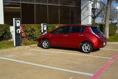 Photo of small red electric vehicle at a charging station