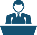 Blue icon of man in suit at a podium with microphones about to speak